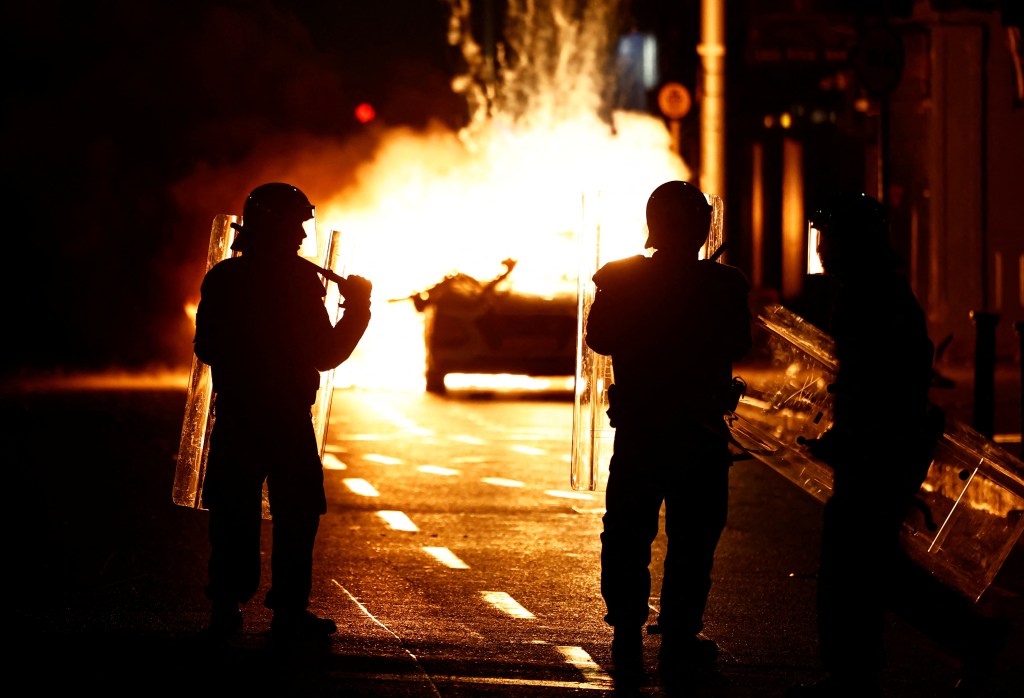 Riot police stands next to a burning police vehicle, near the scene of a suspected stabbing that left few children injured in Dublin, Ireland, November 23, 2023. REUTERS/Clodagh Kilcoyne