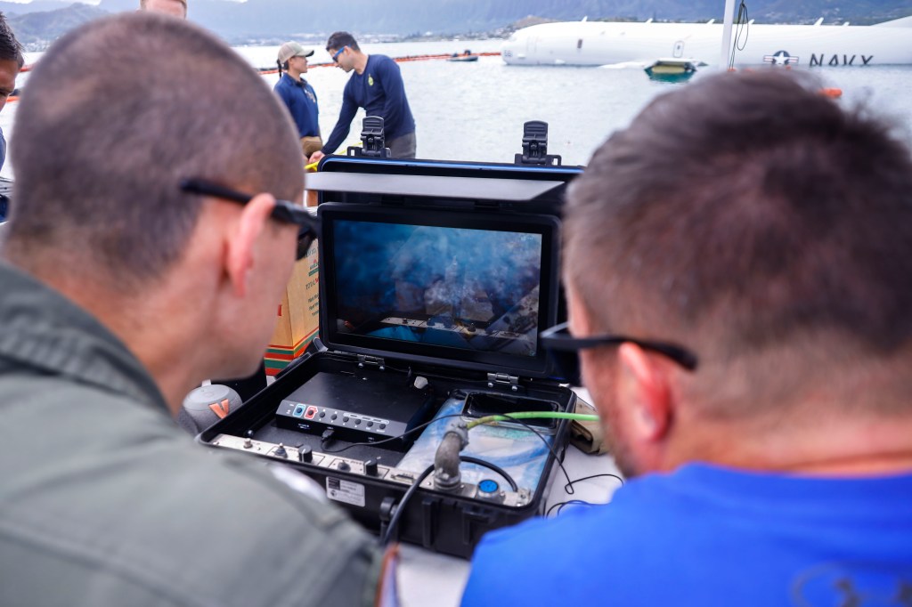 U.S. Navy Sailors with Company 1-3, Mobile Diving and Salvage Unit 1 and Patrol Squadron 4 monitor a submerged diver during defueling operations on a downed U.S. Navy P-8A Poseidon in waters just off the runway at Marine Corps Air Station Kaneohe Bay, Marine Corps Base Hawaii, Nov. 26, 2023. The successful defueling of the downed P-8A was critical to the execution of the aircraft salvage plan. (U.S. Marine Corps photo by Sgt. Brandon Aultman)