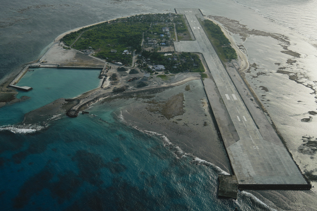 Philippine-occupied Thitu island, locally called Pag-asa island on Friday, Dec. 1, 2023, at the disputed South China Sea, is seen through an aircraft window. The Philippine coast guard inaugurated a new monitoring base Friday on a remote island occupied by Filipino forces in the disputed South China Sea as Manila ramps up efforts to counter China's increasingly aggressive actions in the strategic waterway. (AP Photo/Aaron Favila)