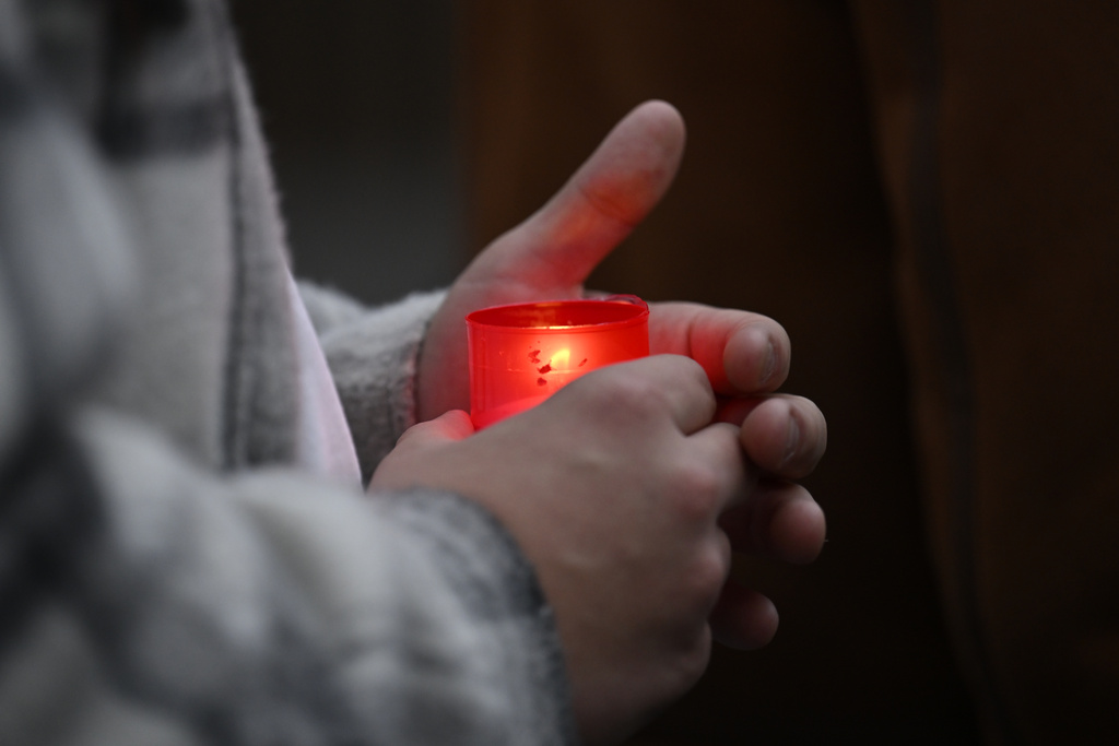 A mourner holds candle outside the building of Philosophical Faculty of Charles University in Prague, Czech Republic, Friday, Dec. 22, 2023. A lone gunman opened fire at a university on Thursday, killing more than a dozen people and injuring scores of people. (AP Photo/Denes Erdos)