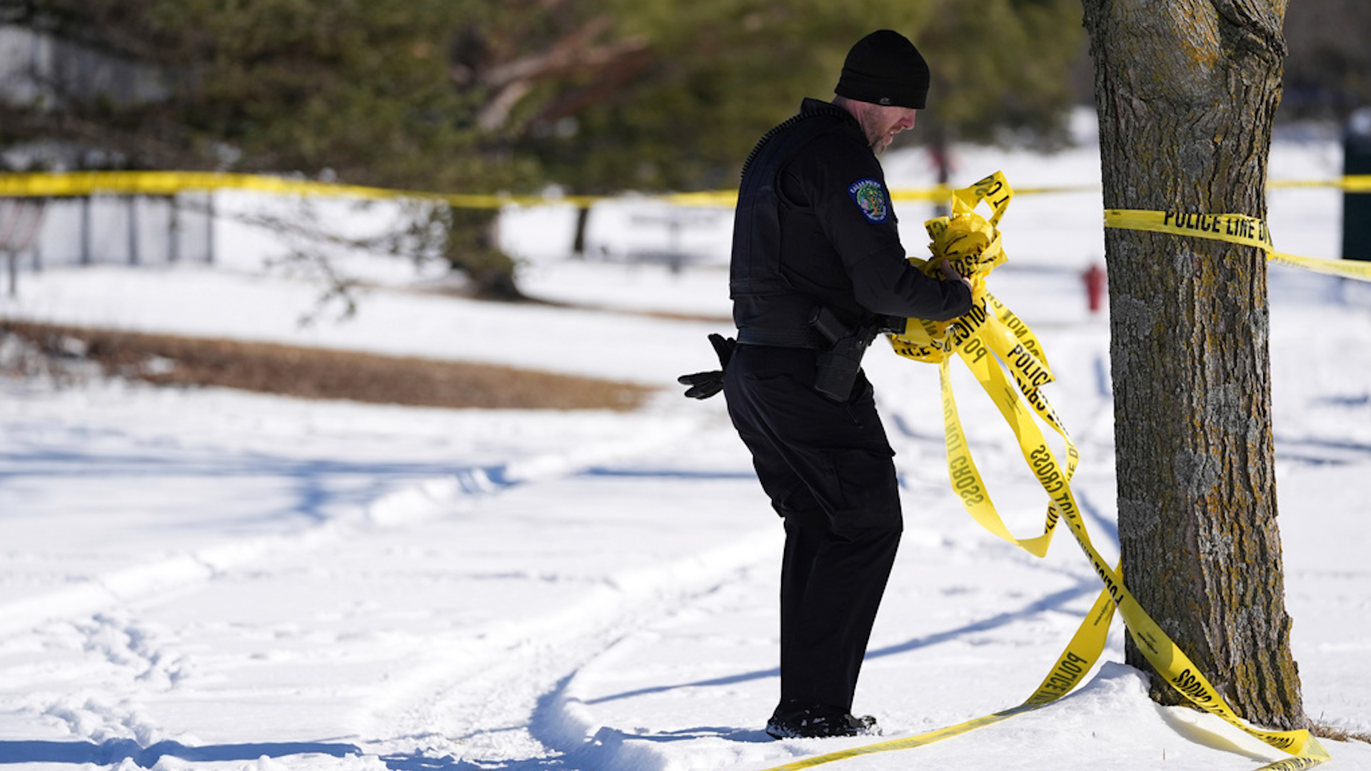 A police officer removes tape near the scene where two police officers and a first responder were shot and killed, Sunday, Feb. 18, 2024, in Burnsville, Minn. (AP Photo/Abbie Parr)